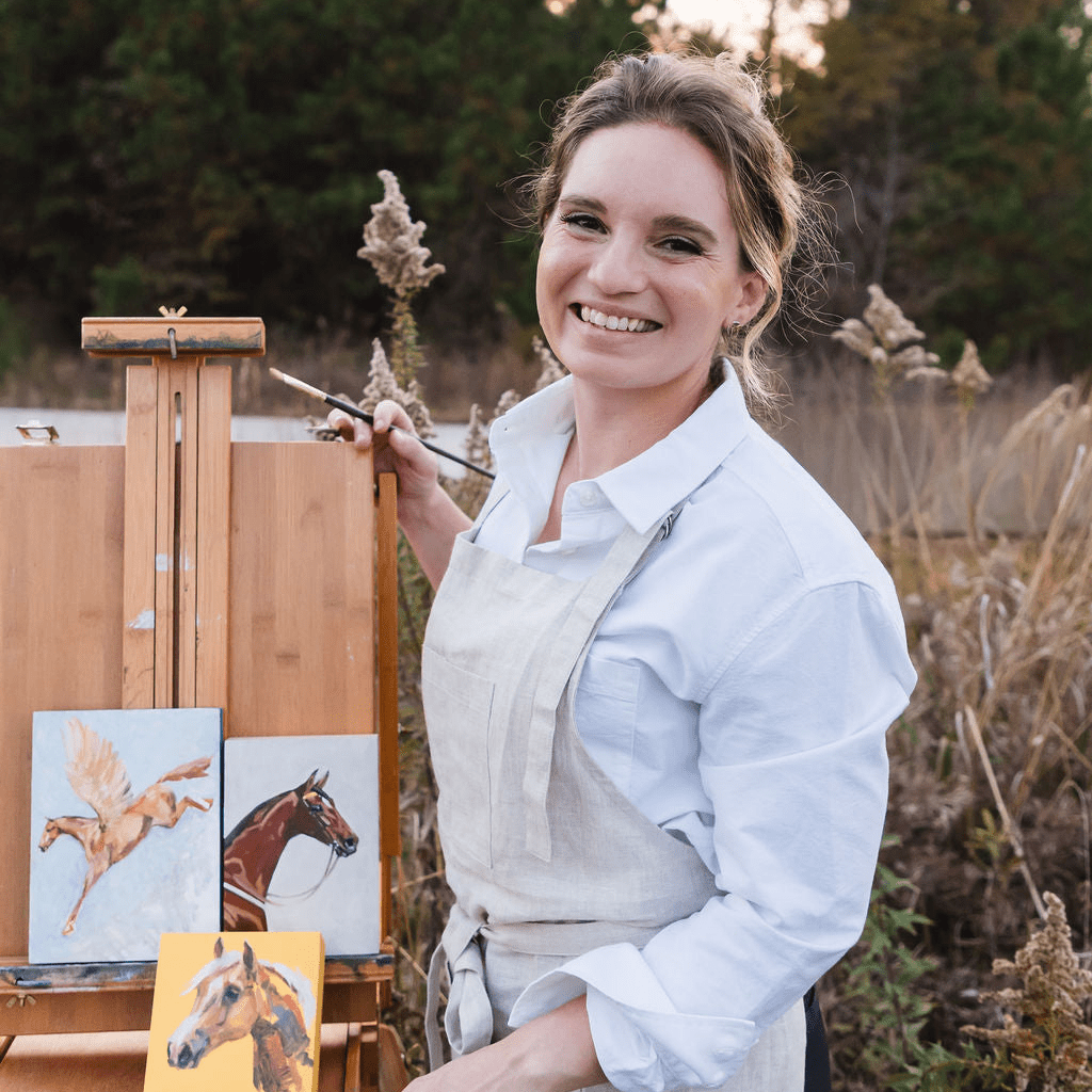 artist Larissa Ann painting horses on an easel in a natural setting