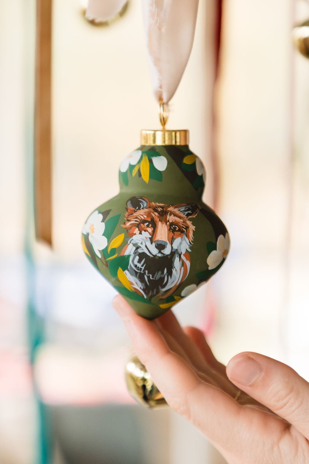 Decorative ornament with a fox design held by a hand against a blurred background