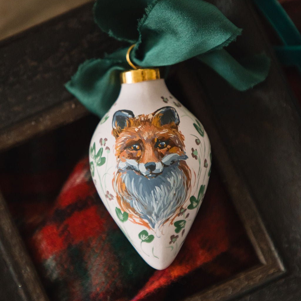 Hand painted decorative porcelain ornament with a fox design on a plaid fabric background