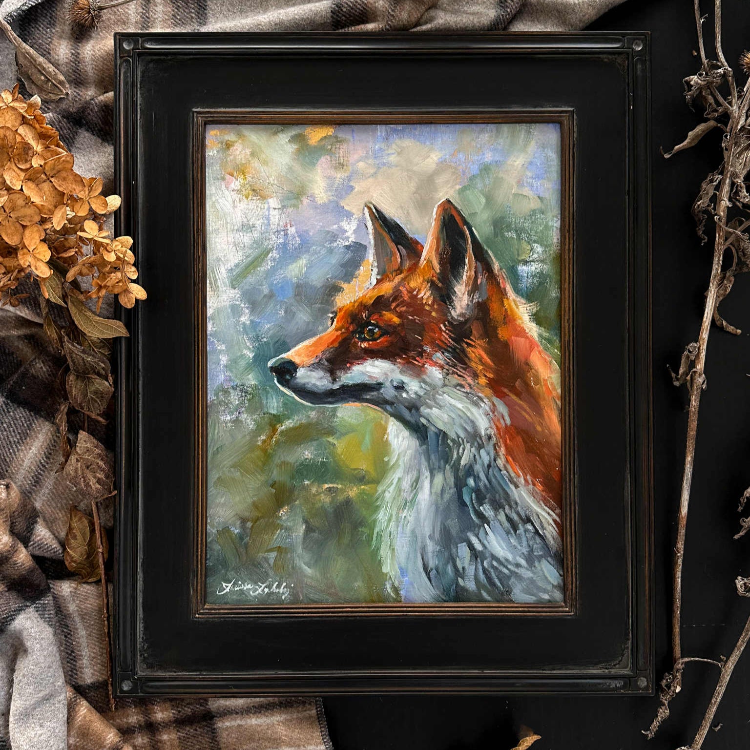 Handsome framed painting of a fox on a textured surface with plaid fabric and dried leaves.