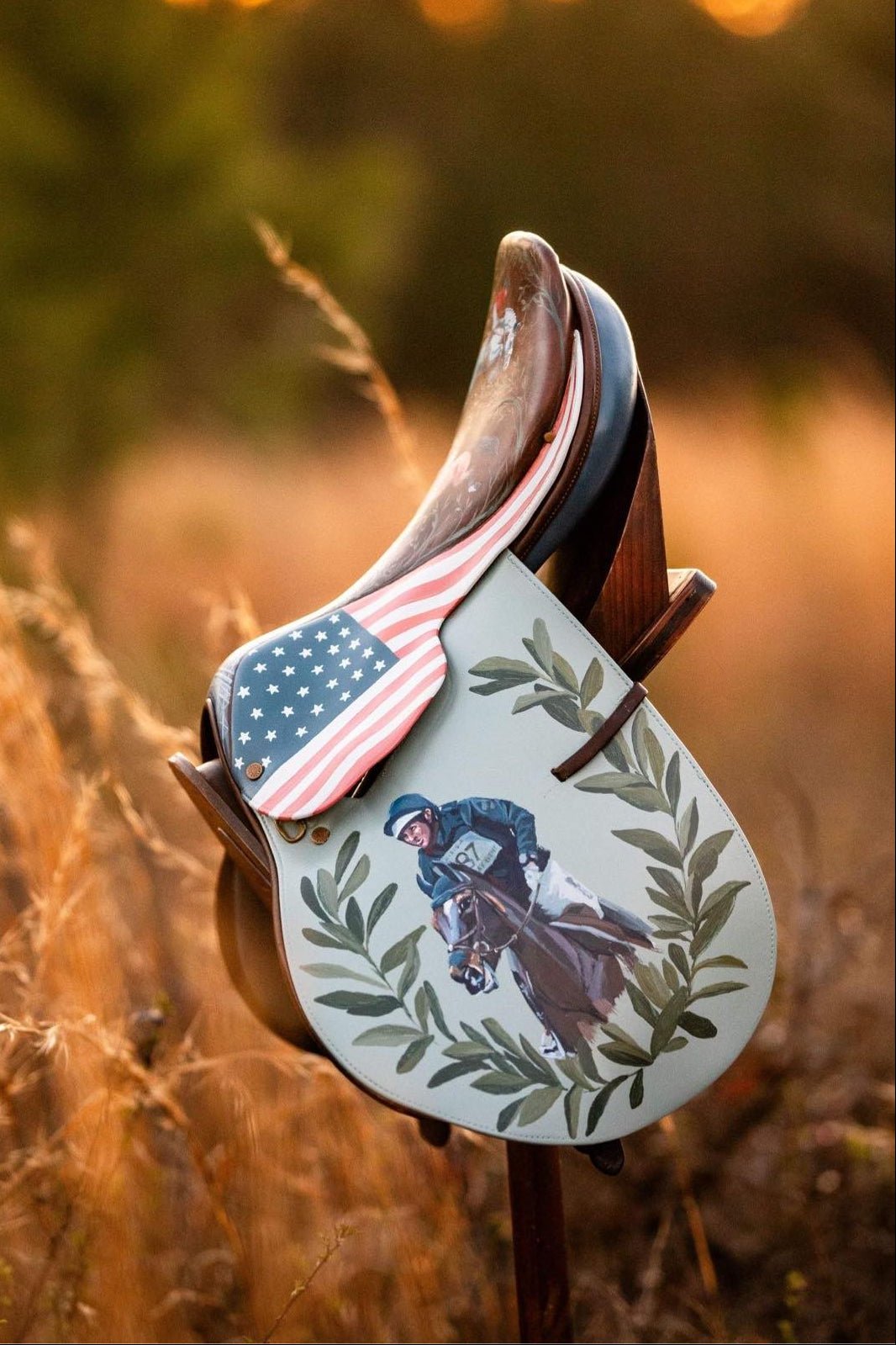 Custom painted saddle with American flag and equestrian featuring olympic eventer Phillip Dutton design in a field at sunset