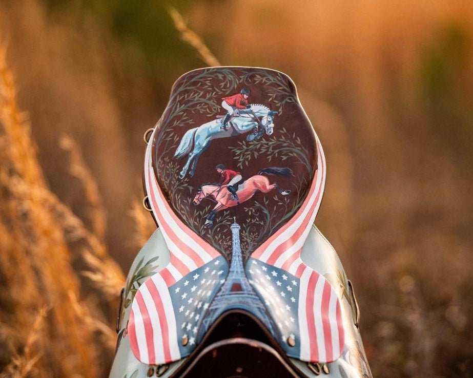 Decorative painted horse saddle with intricate designs and American flag pattern against a blurred natural background