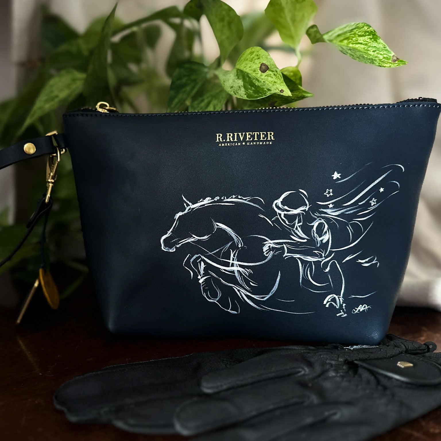 A bespoke hand painted leather clutch bag with equestrian design by artist Larissa Ann