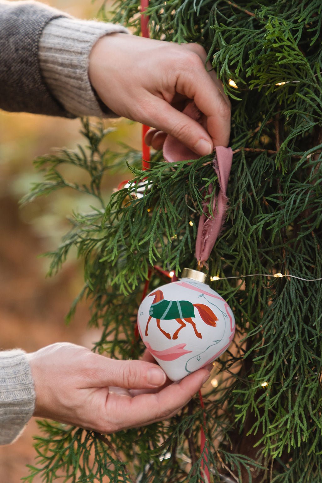 Hand holding a decorated Christmas ornament on a tree