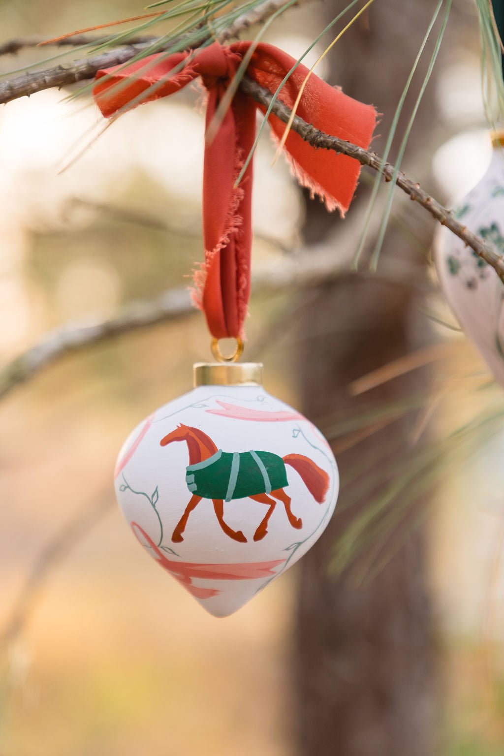 Decorative ornament with a horse design hanging from a branch.