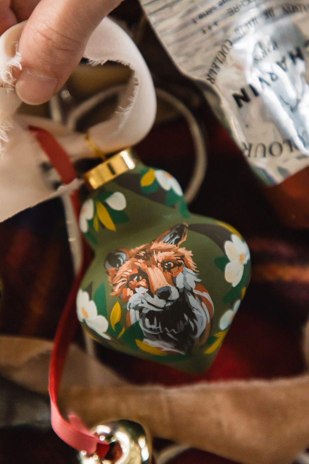 Decorative ornament with a fox design held by a hand against a blurred background.