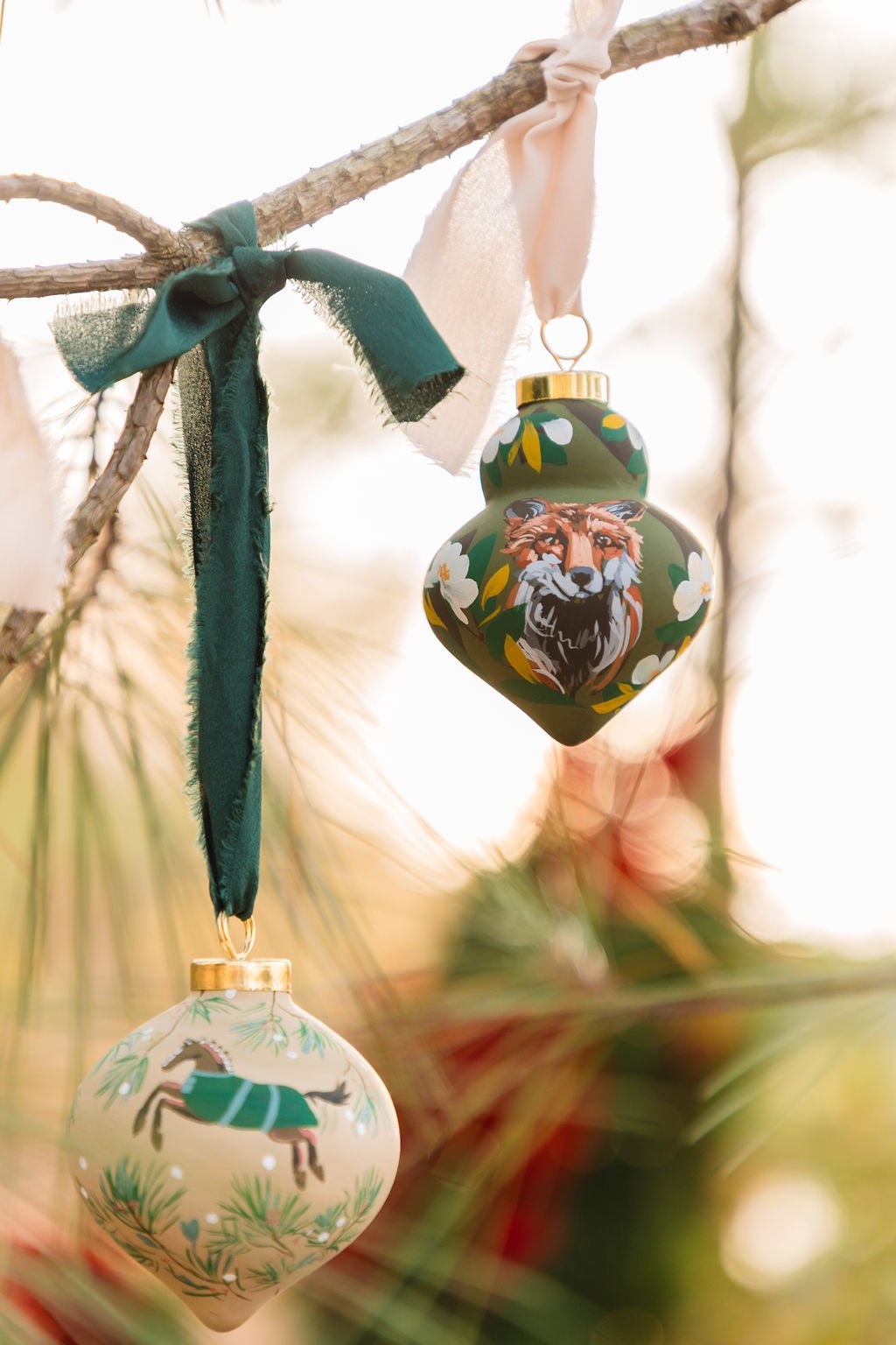 Decorative Christmas ornaments with animal illustrations hanging on a branch.
