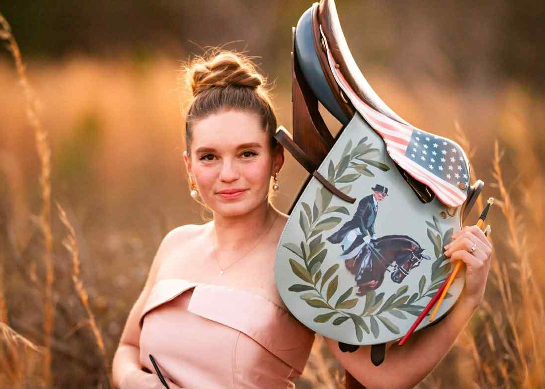 Equestrian artist Larissa Ann with an american flag inspired saddle she painted as a fundraiser for the United States Equestrian Team ahead of the Paris Olympics