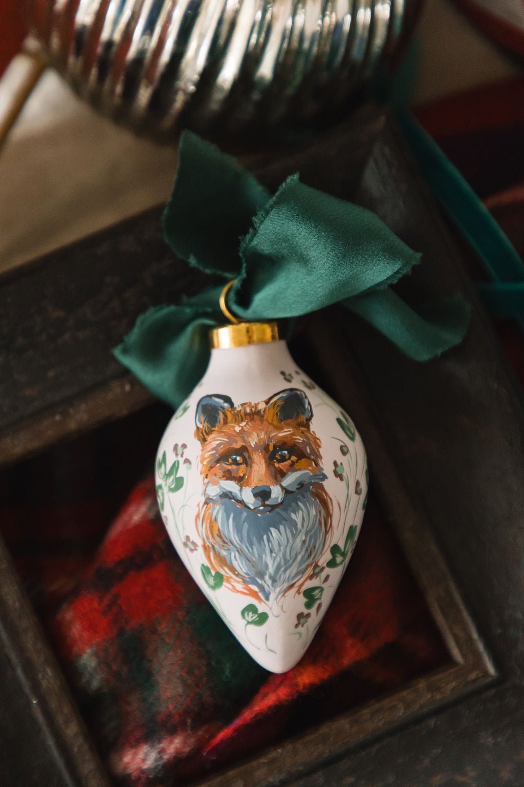 Hand painted decorative porcelain ornament with a fox design on a plaid fabric background
