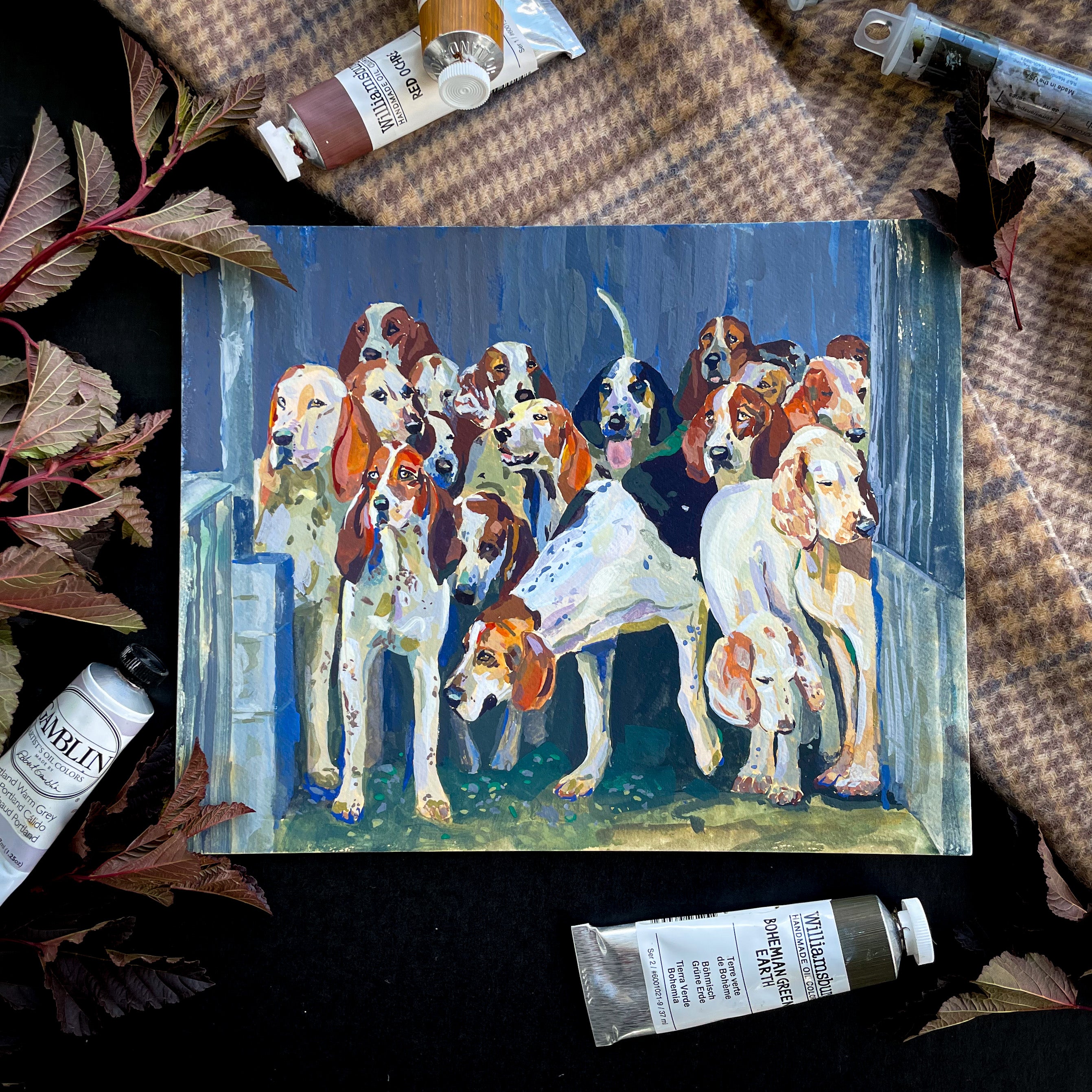 Fox hunting painting of foxhound dogs in a line with art supplies around it.