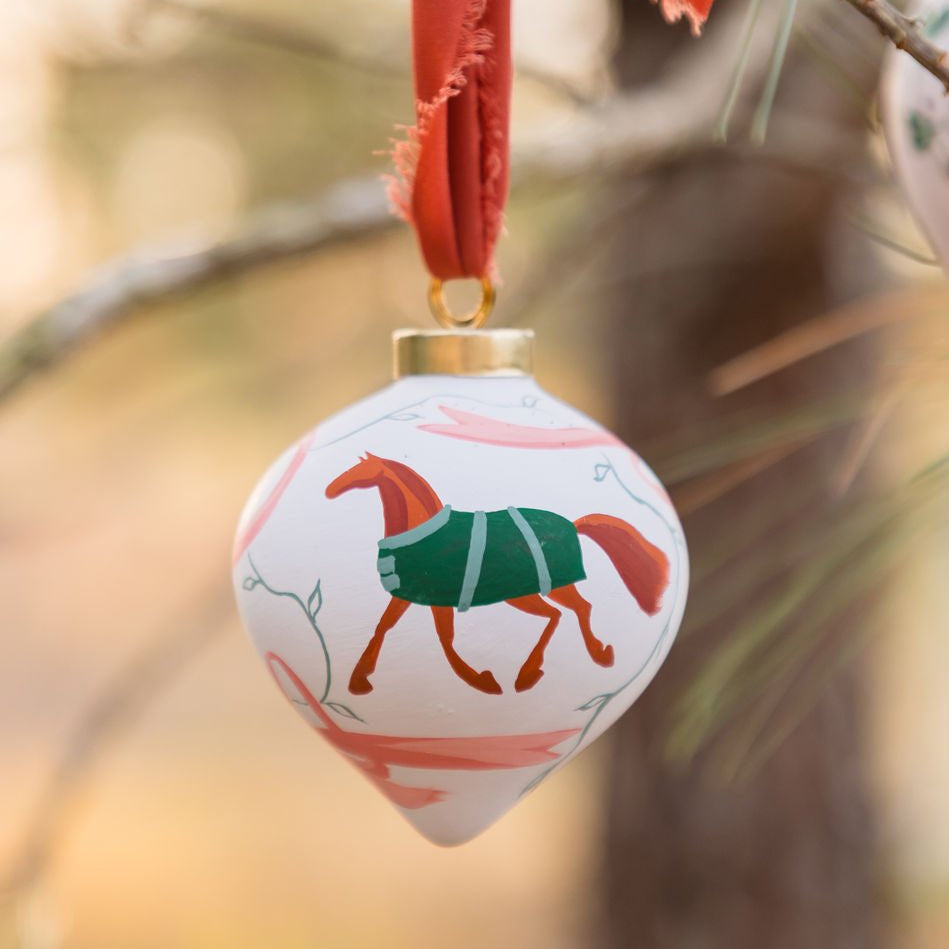 Decorative ornament with a horse design hanging from a branch.